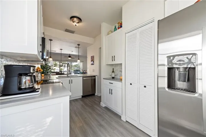 Modern kitchen featuring stainless steel appliances, light wood-finish flooring, and white cabinetry
