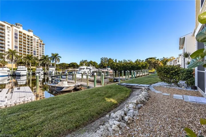 Waterfront property featuring a private boat dock, manicured lawn, paver stone walkway, and established landscaping