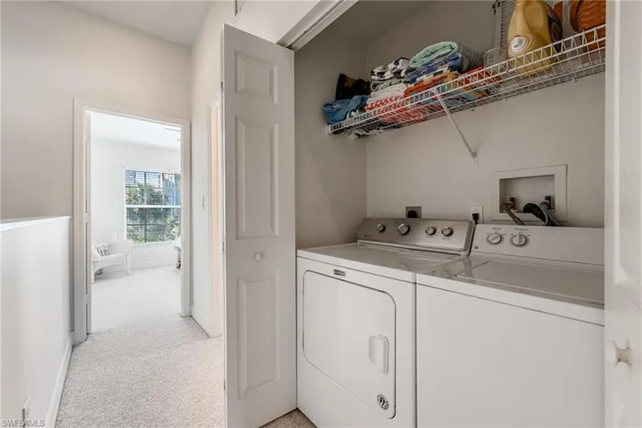 Convenient laundry closet featuring a white washer and dryer set, overhead wire shelving, and bifold doors