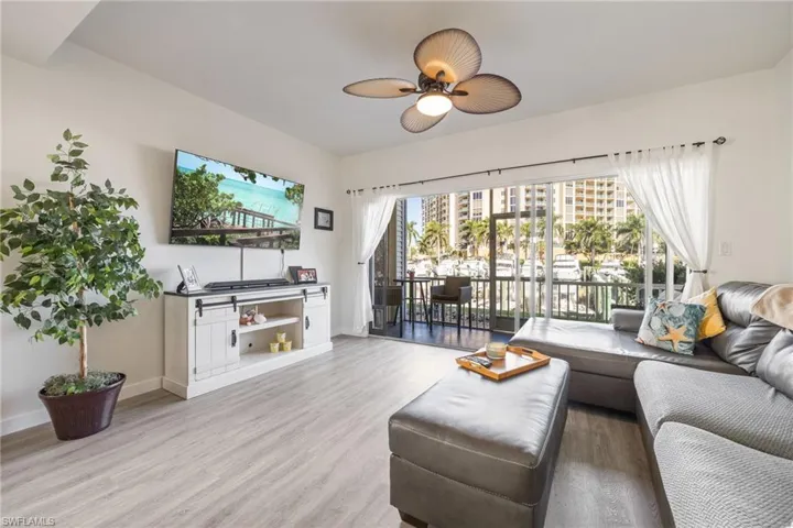 Bright living area featuring wood-finish flooring, a ceiling fan, and sliding glass doors opening to a balcony