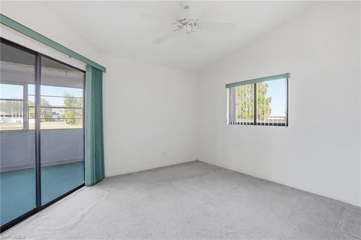 Carpeted spare room featuring ceiling fan and lofted ceiling