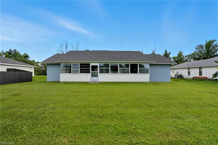 Back of house featuring a yard, roof with shingles, a sunroom, and stucco siding