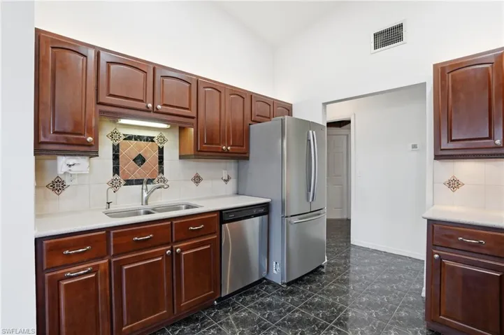 Kitchen featuring backsplash, stainless steel appliances, and a high ceiling
