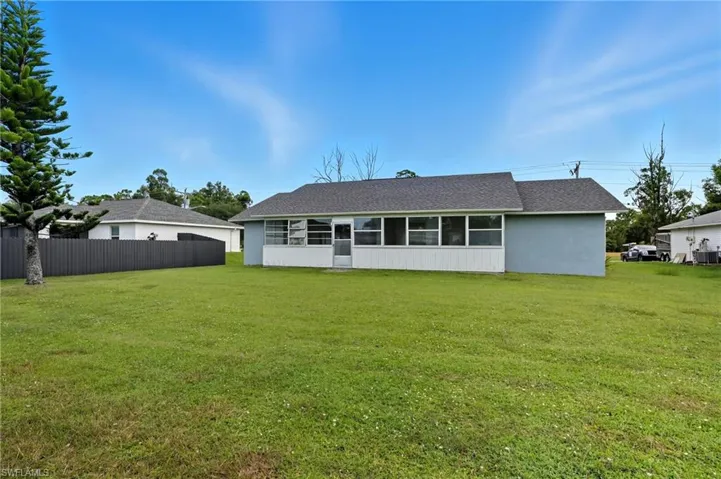 Back of property featuring a sunroom, a shingled roof, and stucco siding