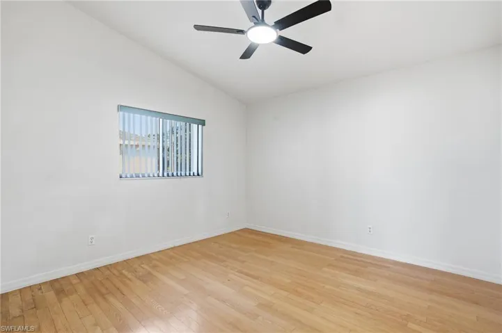 Empty room with light wood-style flooring, lofted ceiling, and ceiling fan