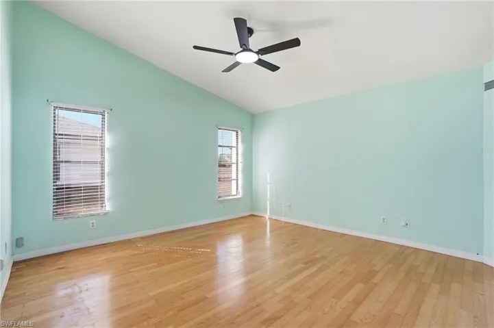 Spare room with ceiling fan, light wood-style flooring, and vaulted ceiling