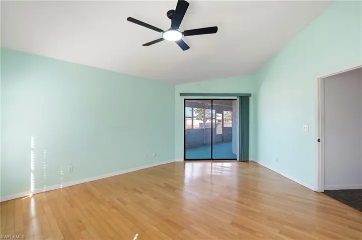 Unfurnished room featuring ceiling fan, hardwood / wood-style flooring, and vaulted ceiling