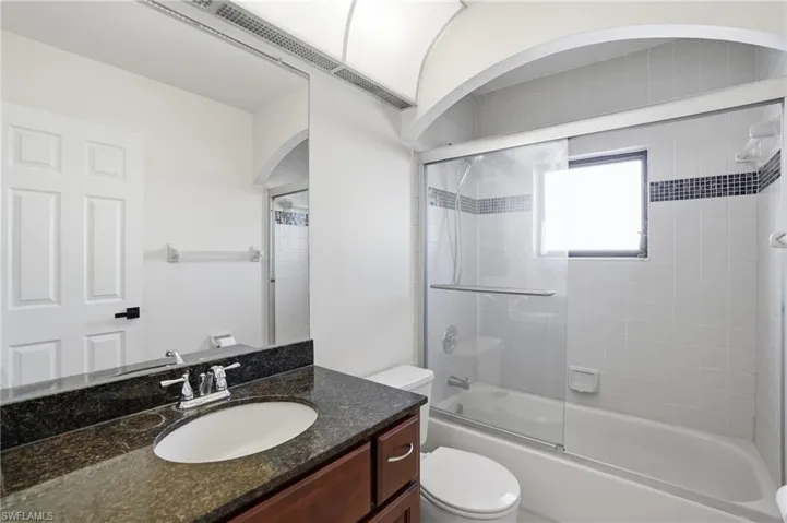 Bathroom with vanity and bath / shower combo with glass door