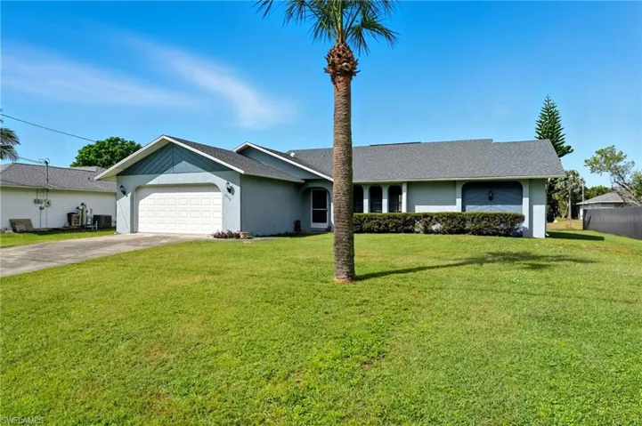 Ranch-style house featuring stucco siding, a front lawn, driveway, and an attached garage