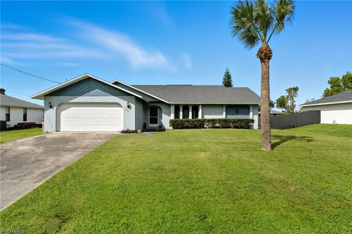 Ranch-style house with stucco siding, driveway, an attached garage, and roof with shingles