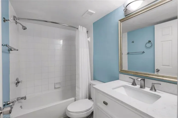 Full bathroom featuring vanity, shower / bath combination with curtain, and toilet