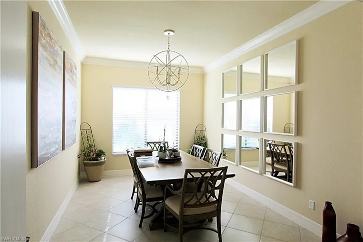 Tiled dining space featuring ornamental molding and a chandelier