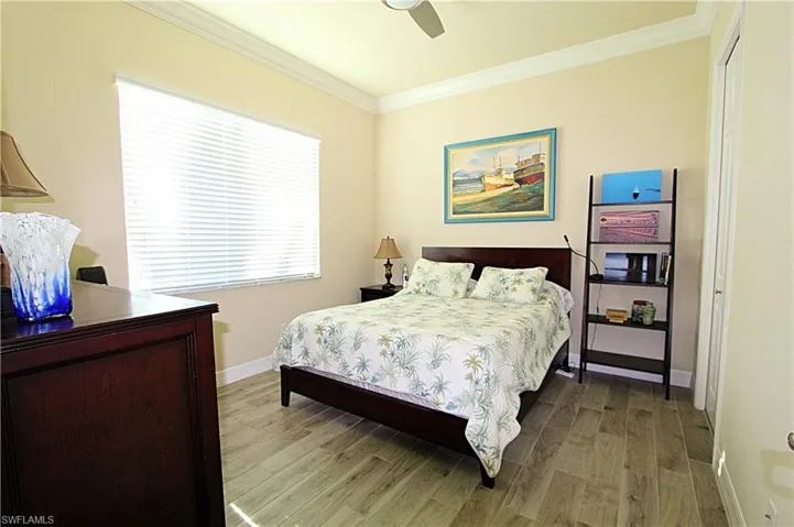 Bedroom with ceiling fan, light hardwood / wood-style flooring, crown molding, and a closet