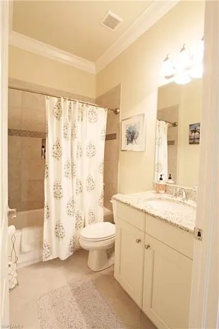 Full bathroom with shower / bathtub combination with curtain, crown molding, vanity, and toilet