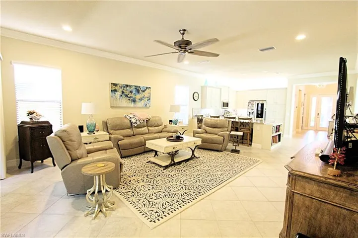 Tiled living room featuring ceiling fan and crown molding