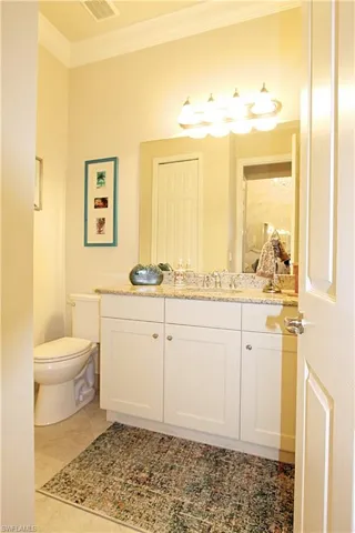 Bathroom featuring ornamental molding, vanity, toilet, and tile patterned floors