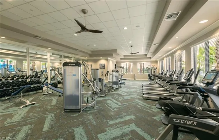 Exercise room featuring ornamental molding, a paneled ceiling, carpet flooring, and ceiling fan