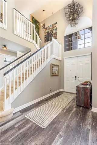 Foyer entrance featuring dark wood-type flooring, a high ceiling, and a chandelier