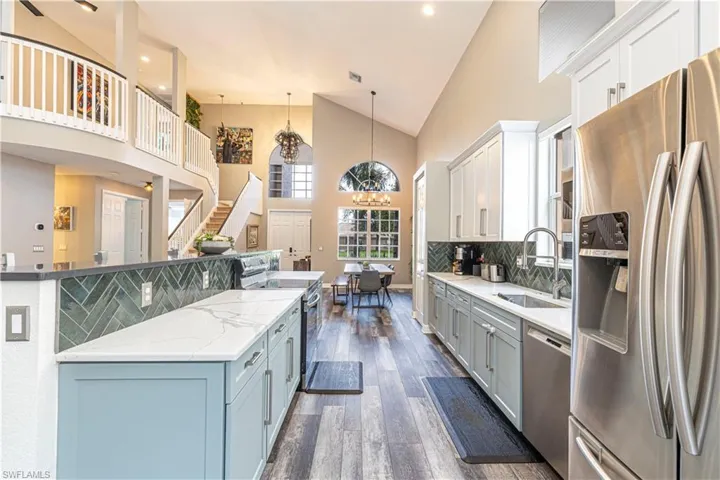 Kitchen with stainless steel appliances, white cabinets, dark hardwood / wood-style floors, decorative light fixtures, and tasteful backsplash
