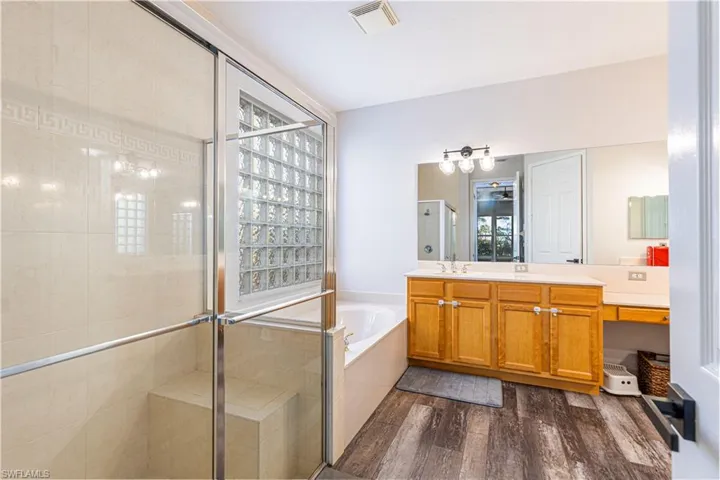 Bathroom with a wealth of natural light, wood-type flooring, vanity, and shower with separate bathtub