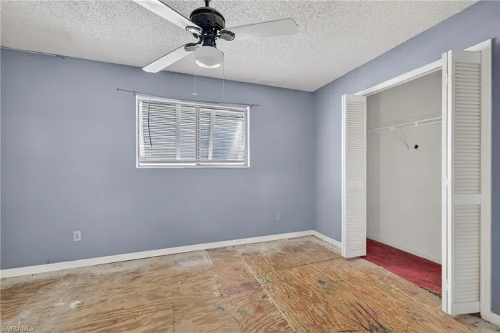Unfurnished bedroom with a closet, a ceiling fan, and a textured ceiling