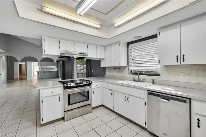 Kitchen with a peninsula, appliances with stainless steel finishes, white cabinetry, and light countertops