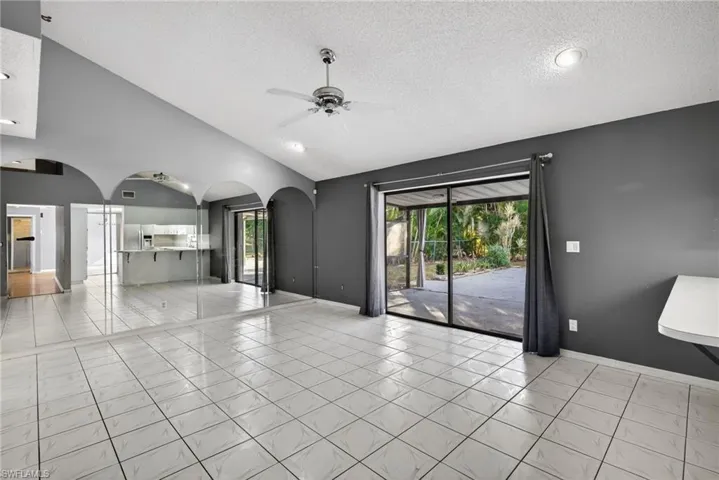 Unfurnished living room featuring light tile patterned floors, ceiling fan, arched walkways, a textured ceiling, and recessed lighting