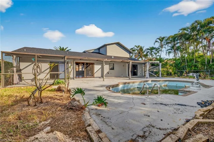 Rear view of house featuring a patio area, an outdoor pool, roof with shingles, and a sunroom