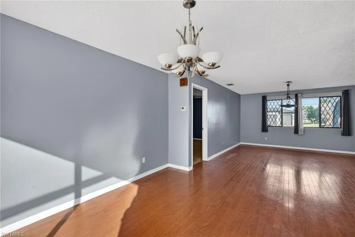 Unfurnished room featuring a chandelier, a textured ceiling, and dark wood-type flooring