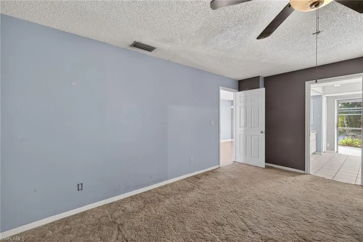 Unfurnished bedroom featuring a textured ceiling, carpet flooring, and a ceiling fan