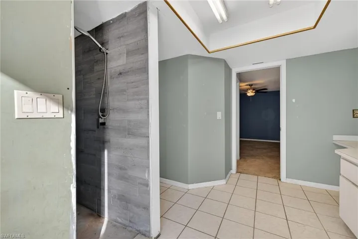 Full bathroom featuring tiled shower, vanity, a ceiling fan, and light tile patterned flooring