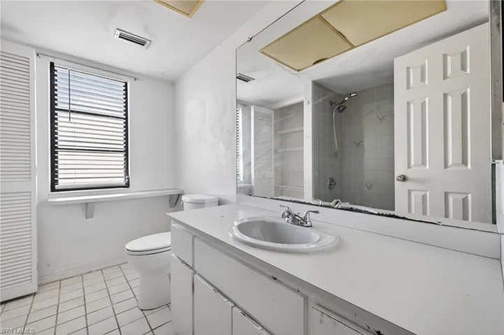 Full bathroom featuring vanity, tiled shower, light tile patterned floors, and a closet