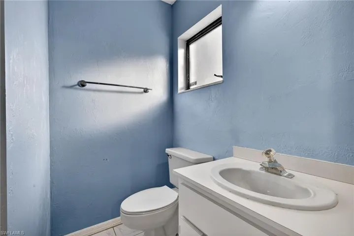Half bathroom featuring a textured wall and vanity