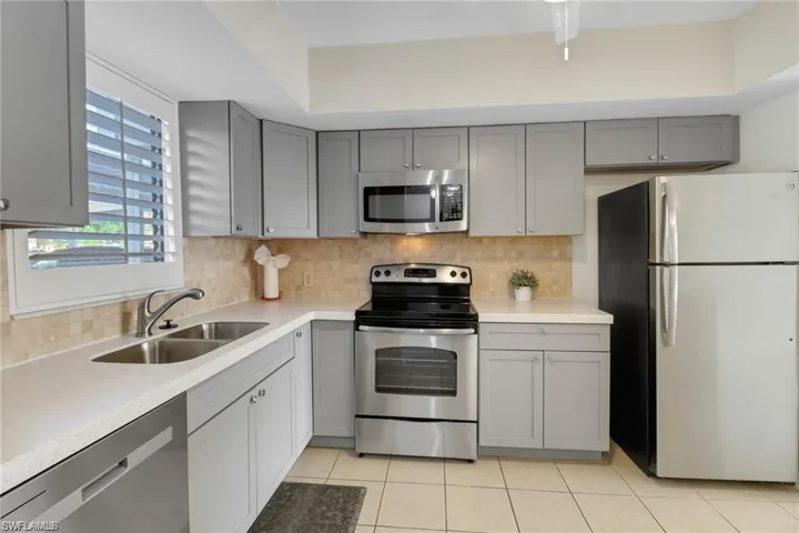 Kitchen featuring light tile patterned floors, appliances with stainless steel finishes, sink, and tasteful backsplash