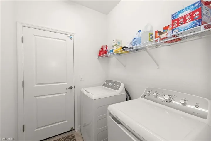 Utility room featuring a white paneled door, light-colored walls, and built-in wire shelving
