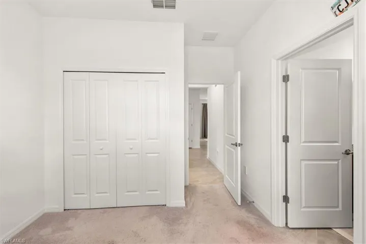 Carpeted room featuring bi-fold closet doors with round knobs