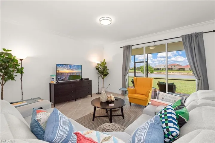Living area featuring a sliding glass door opening to a screened lanai with water views, tile flooring, and crown molding