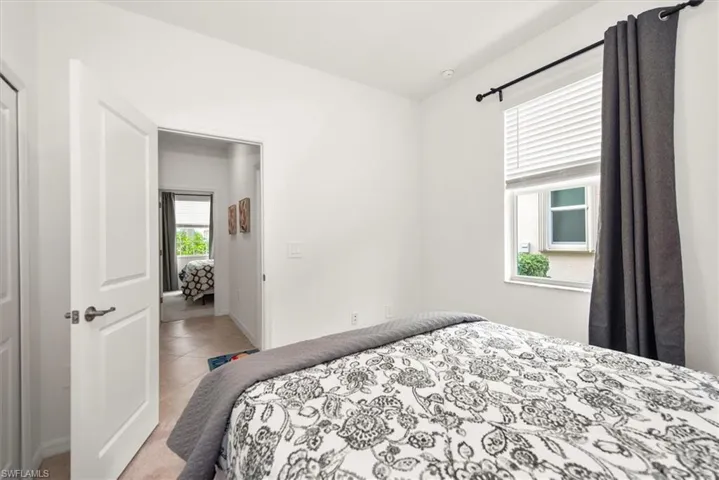 Bright interior space featuring a window with white blinds and a dark curtain rod