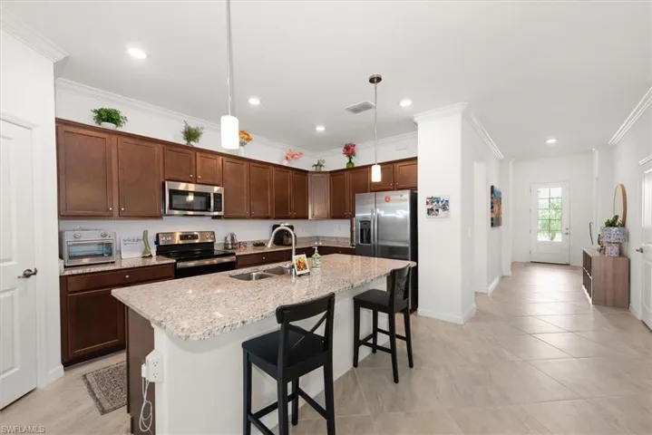 Modern kitchen featuring dark wood cabinetry, stainless steel appliances, granite countertops, and a central island with bar seating