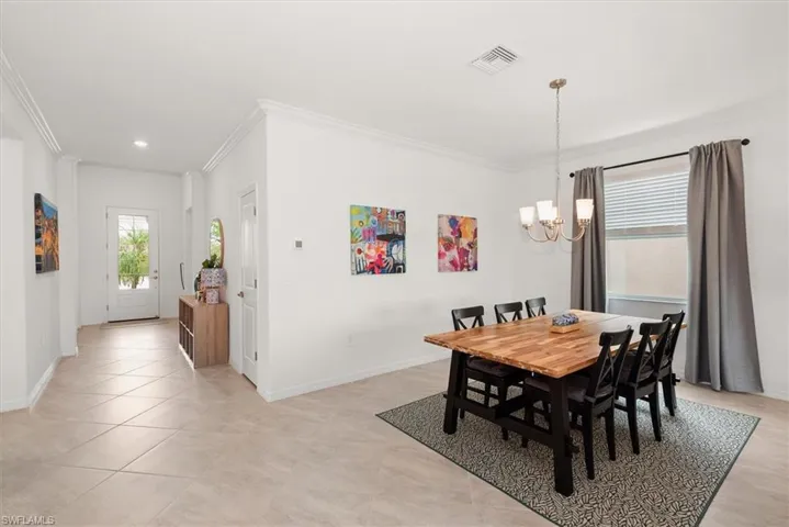 Dining area featuring a brushed bronze chandelier and a window with blinds and drapes