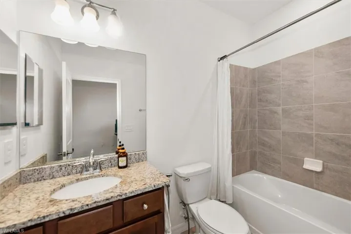 Bathroom featuring a dark wood vanity with a granite countertop, undermount sink, and a large wall-mounted mirror