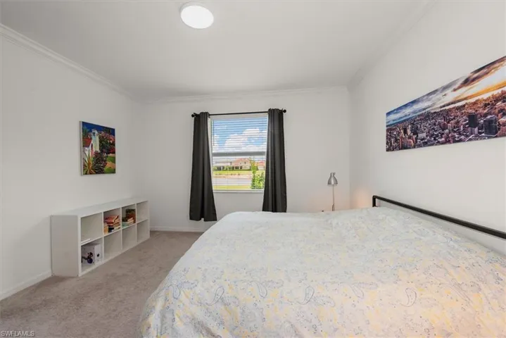 Carpeted interior space featuring crown molding, a window with blinds and dark curtains, and a flush-mount ceiling light fixture