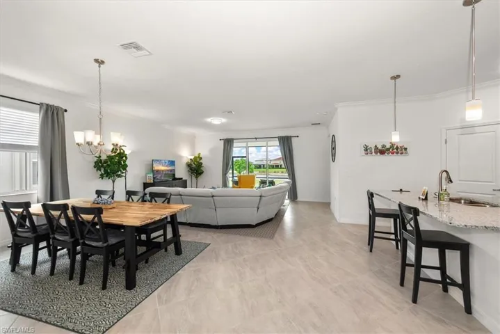 Open-concept living area featuring light-toned flooring, crown molding, and recessed lighting