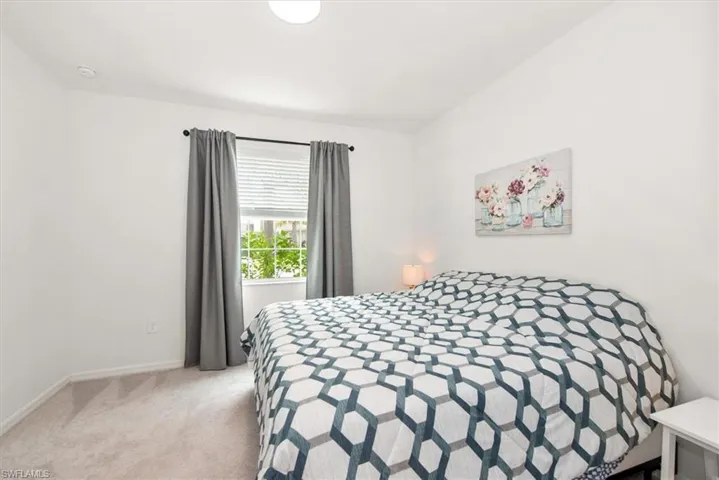 Carpeted bedroom featuring a window with blinds and dark drapery, white walls, and a flush-mount ceiling light