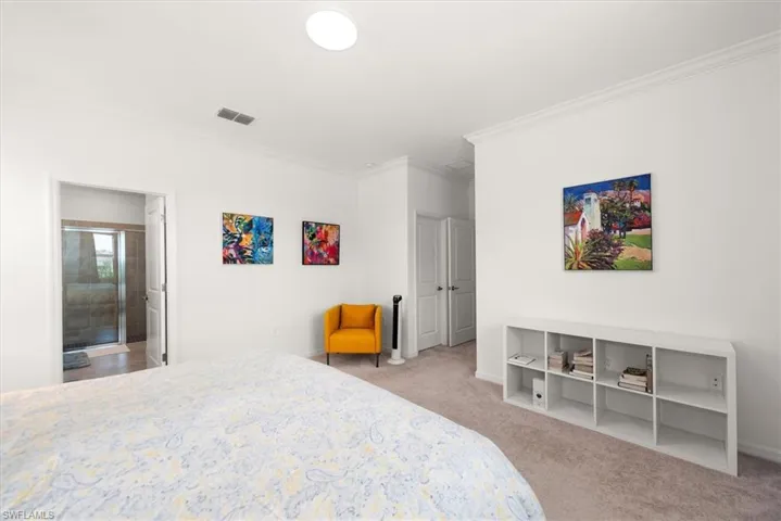 Bedroom featuring light-colored carpeting, white walls, and crown molding