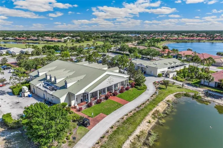 Overhead view of a community building with a green roof, set within a landscaped area featuring lawns, trees, and a visible pond