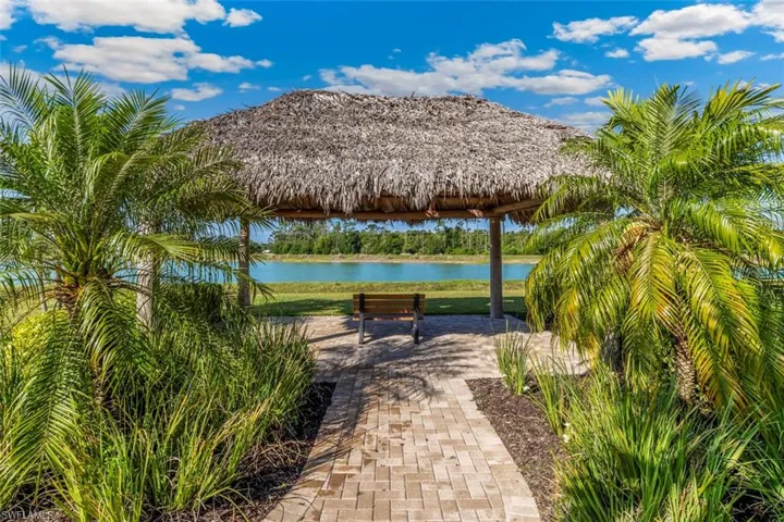 This property features a thatched-roof gazebo with a paved pathway, surrounded by lush tropical landscaping and palm trees