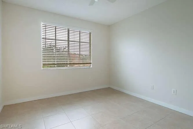 Spare room with ceiling fan, a healthy amount of sunlight, and light tile floors