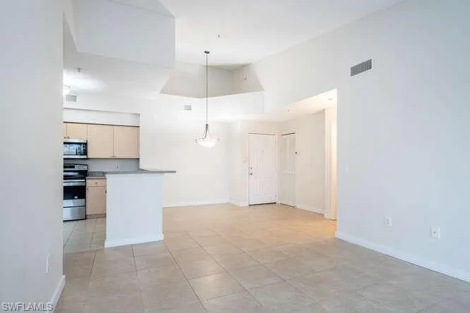Kitchen with hanging light fixtures, a high ceiling, range, and light tile flooring