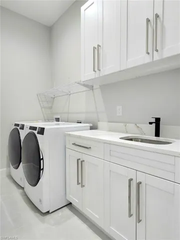 Washroom with cabinets, sink, and washing machine and clothes dryer